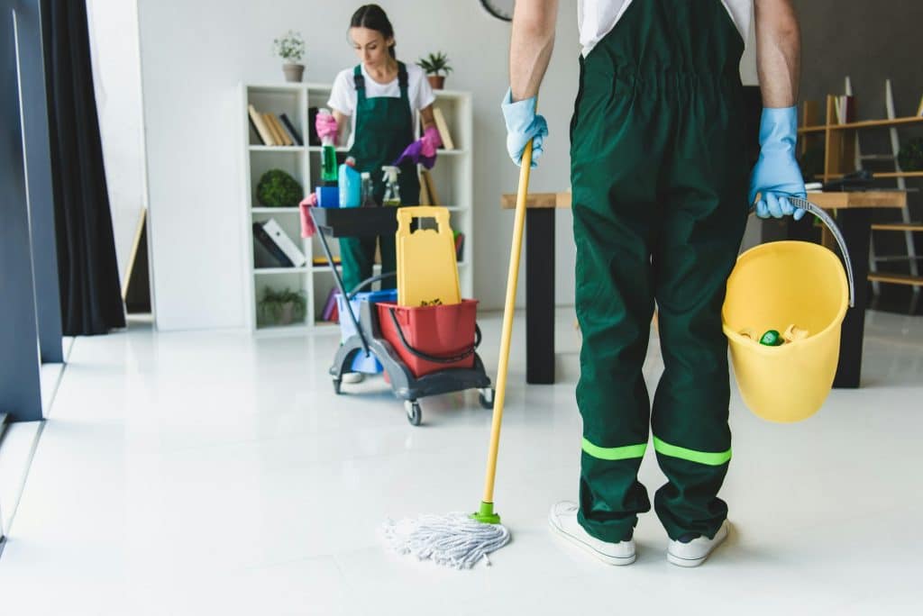 cropped shot of young cleaning company workers holding various cleaning equipment in office